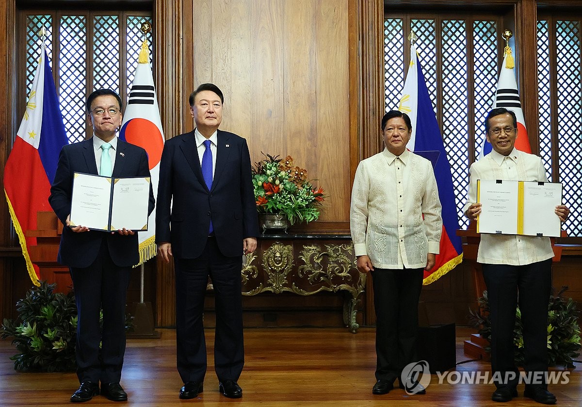 Choi Sang-mok (L), South Korea's finance minister and deputy prime minister, and Alcenio Barisakan (R), Secretary of the National Economic and Development Authority of the Philippines, exchange a memorandum of understanding on the Economic Innovation Partnership Program at the Malacanang Palace in Manila on Oct. 7, 2024. South Korean President Yoon Suk Yeol (2nd from L) and Philippine President Ferdinand Marcos Jr. attended the ceremony. (Yonhap)