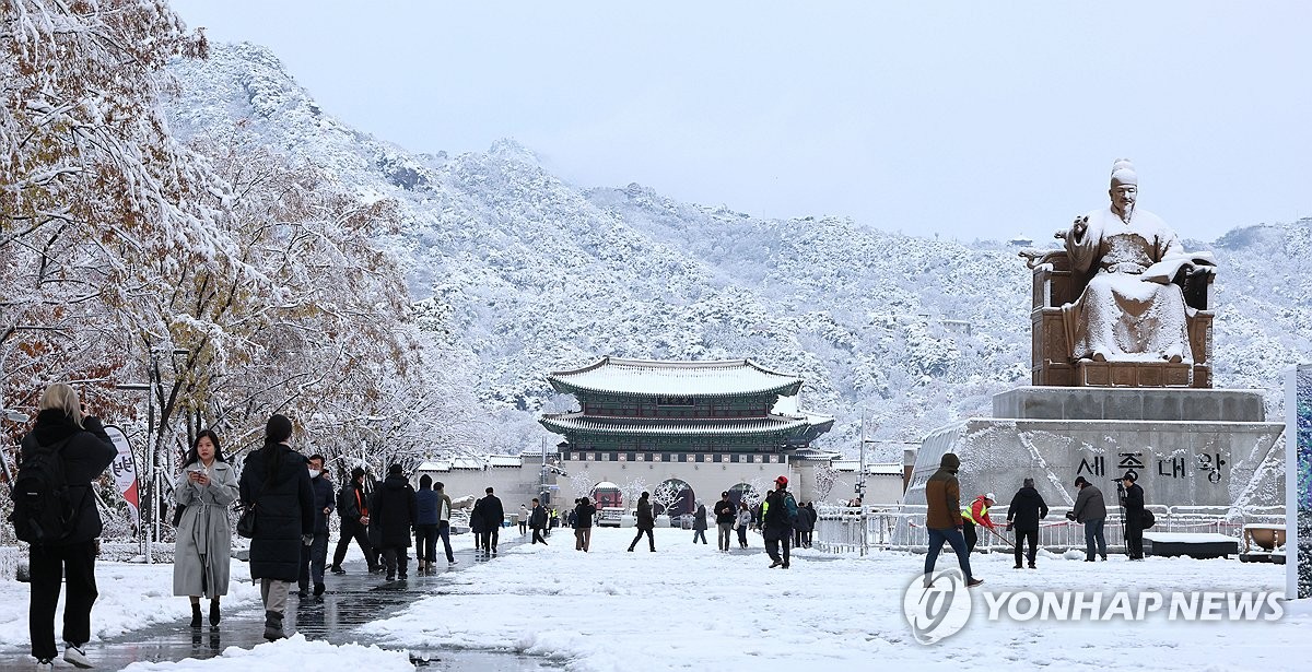 La gente camina en la plaza Gwanghwamun en Seúl mientras las fuertes nevadas se acumulaban en la ciudad el 27 de noviembre de 2024. (Yonhap)