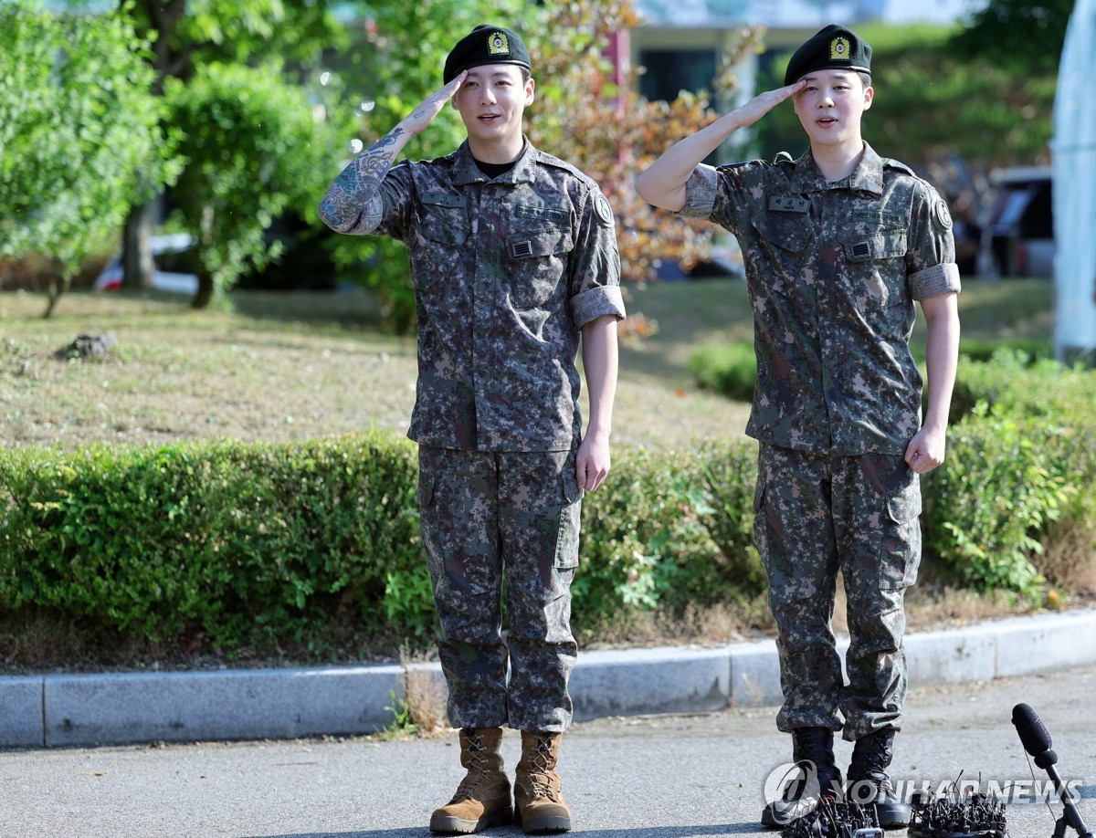 Jungkook (izda.) y Jimin, del megagrupo de K-pop BTS, saludan tras ser licenciados del servicio militar obligatorio, el 11 de junio de 2025, en la comarca de Yeoncheon, en la provincia de Gyeonggi.